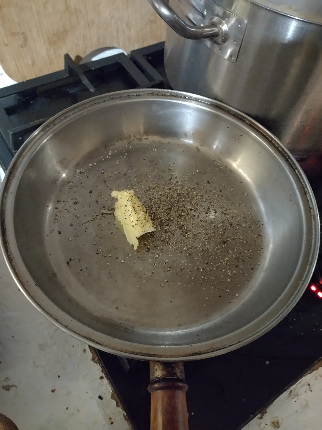 Freshly ground black pepper and butter in a stainless steel saucepan, building the cacio e pepe sauce base