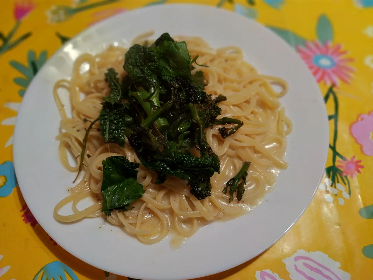 Cacio e pepe with charred winter greens on a white plate