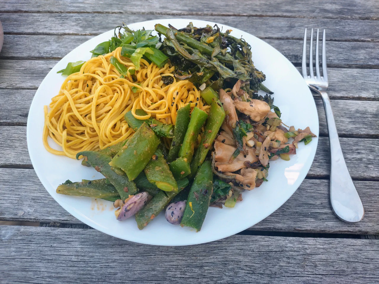 Plated pink oyster mushroom stir-fry with noodles and garden herbs
