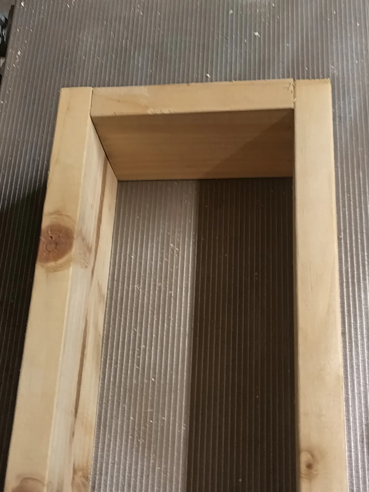 An assembled timber cradle viewed from above showing the open channel that will hold the gutter, with decking plank sides and end pieces forming a neat rectangular frame