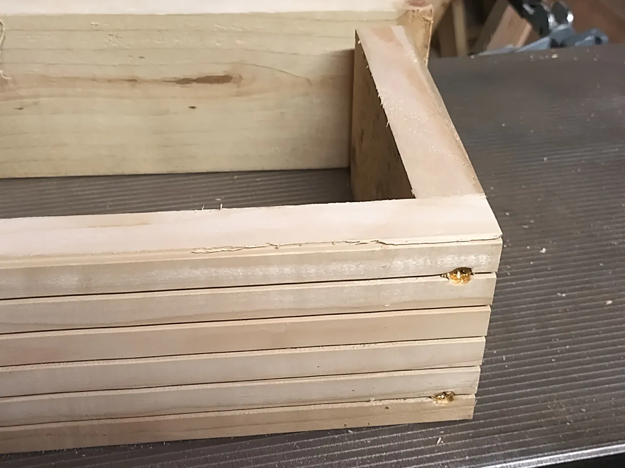 Close-up of a timber cradle corner showing the end piece screwed to the side length with a spacer block visible between the two planks