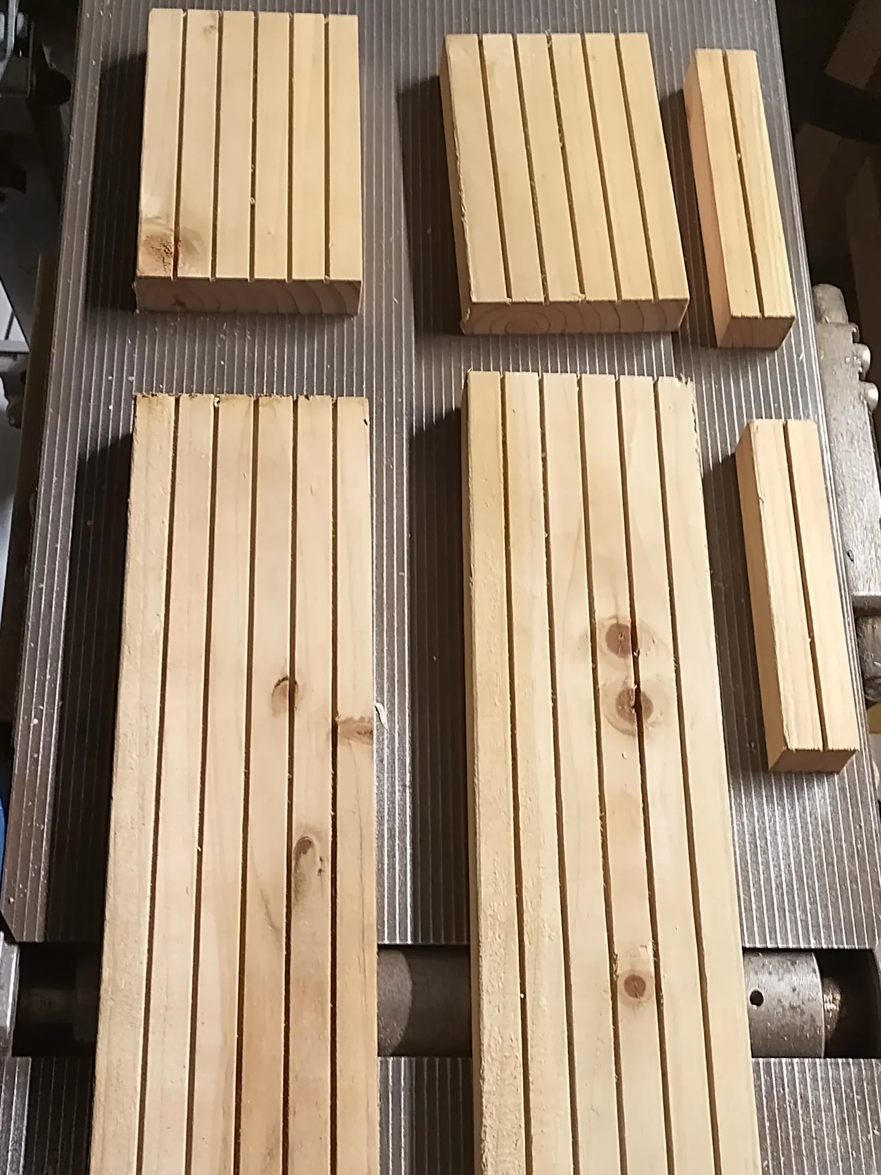 Decking plank pieces cut on the table saw — two long side lengths and several short end pieces and spacer blocks, all ripped to the correct height for the gutter