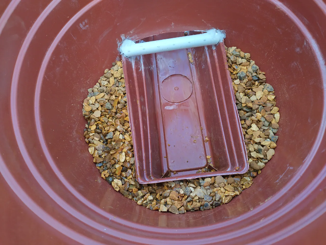 Gravel layer filling the base of the pot around the trough, up to trough level