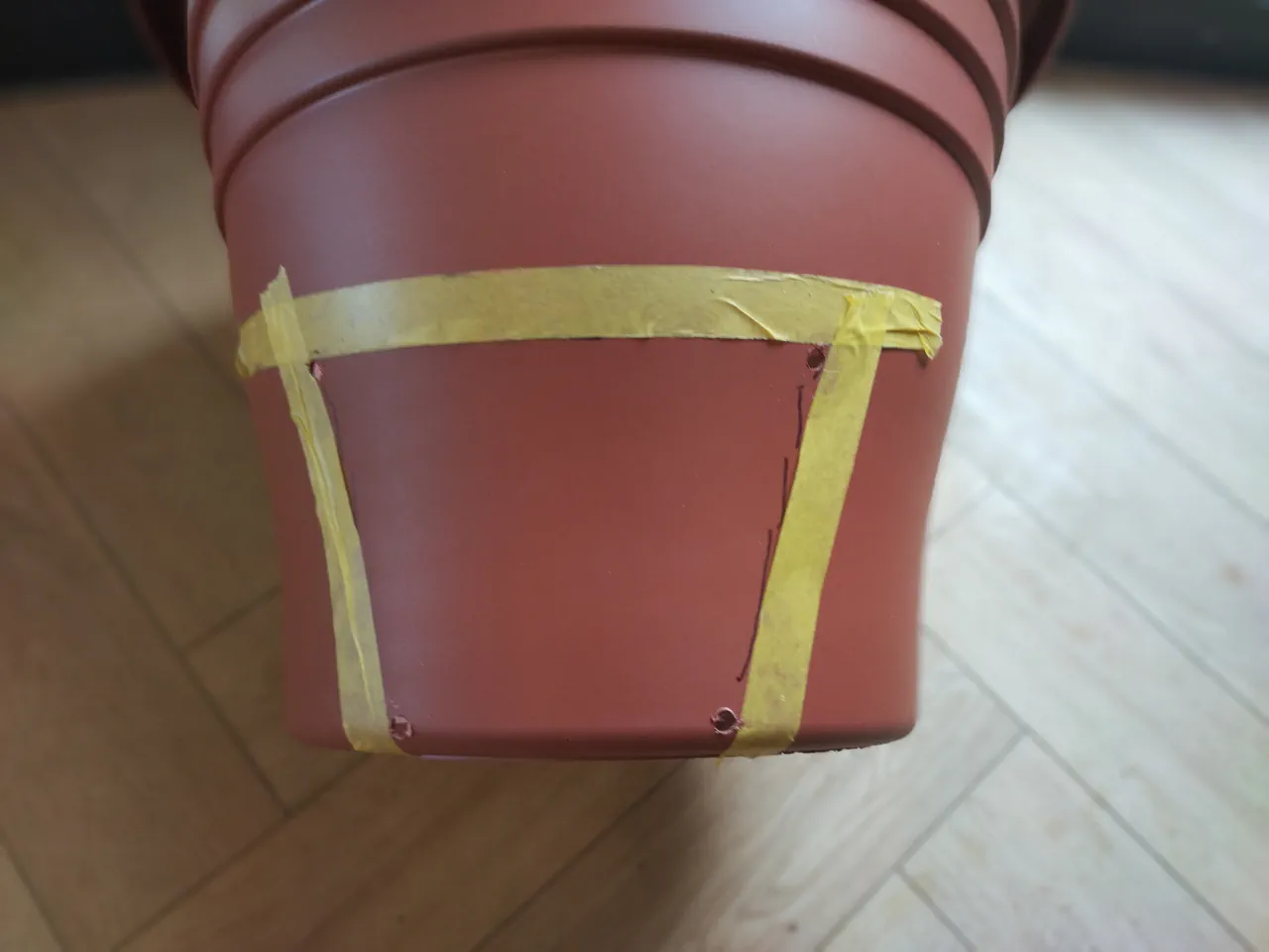 Masking tape applied to the pot along the marked cut lines, with corners clearly defined