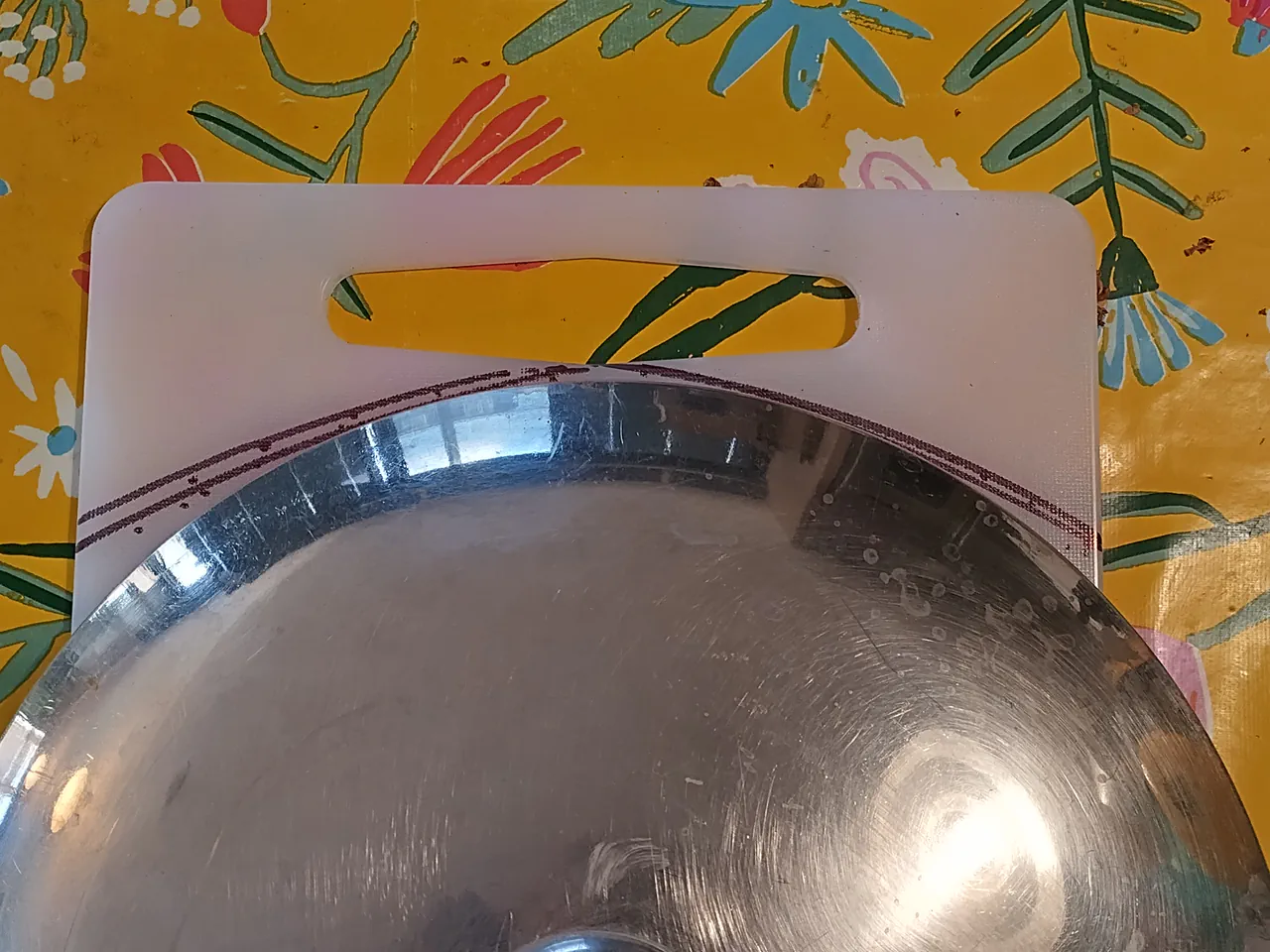 A saucepan lid placed on the chopping board as a circular template for tracing the cut line