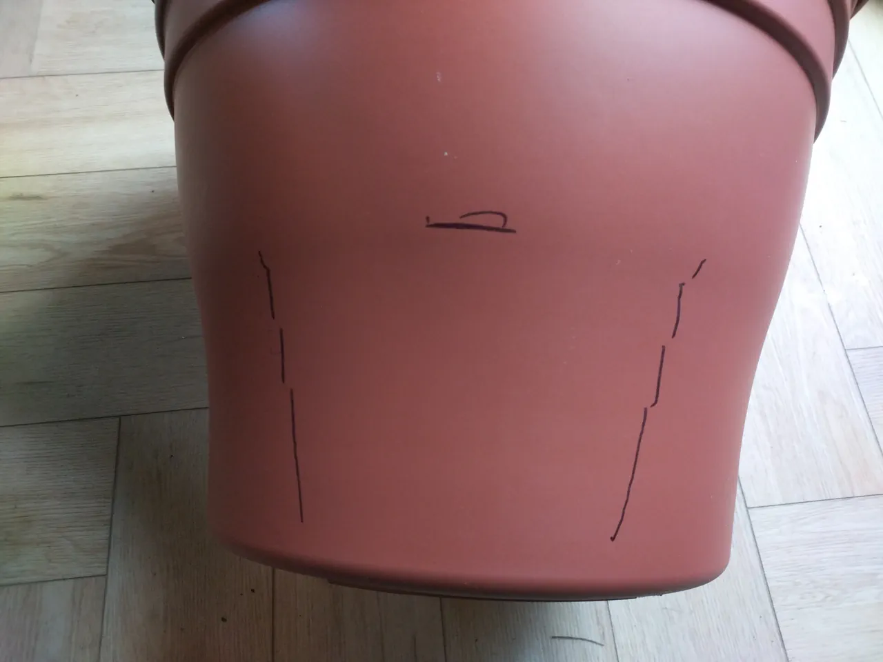 Sharpie held horizontally between the pot and trough, both sitting flat on a surface, drawing the outline of the trough hole onto the pot