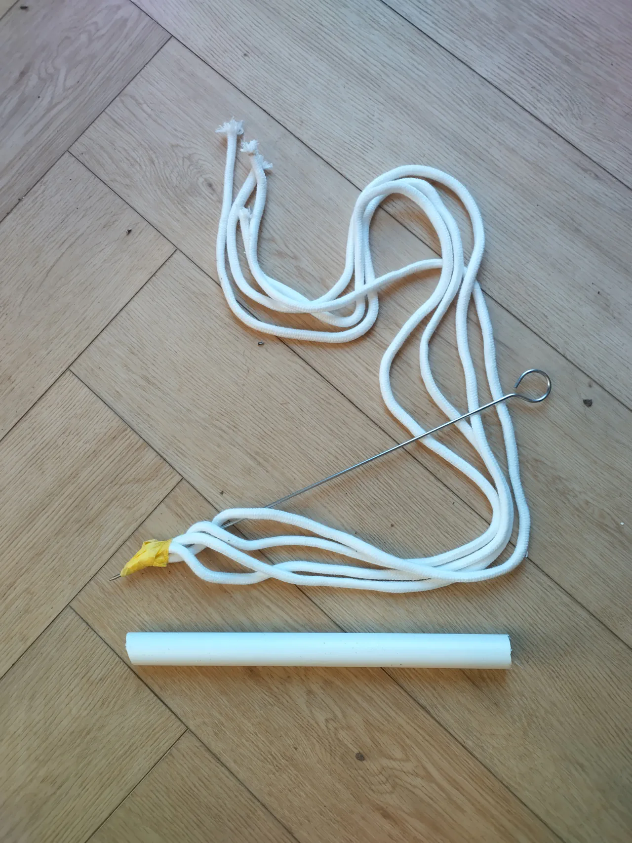 Four lengths of white wicking rope alongside masking tape, a wooden skewer, and a short piece of PVC pipe