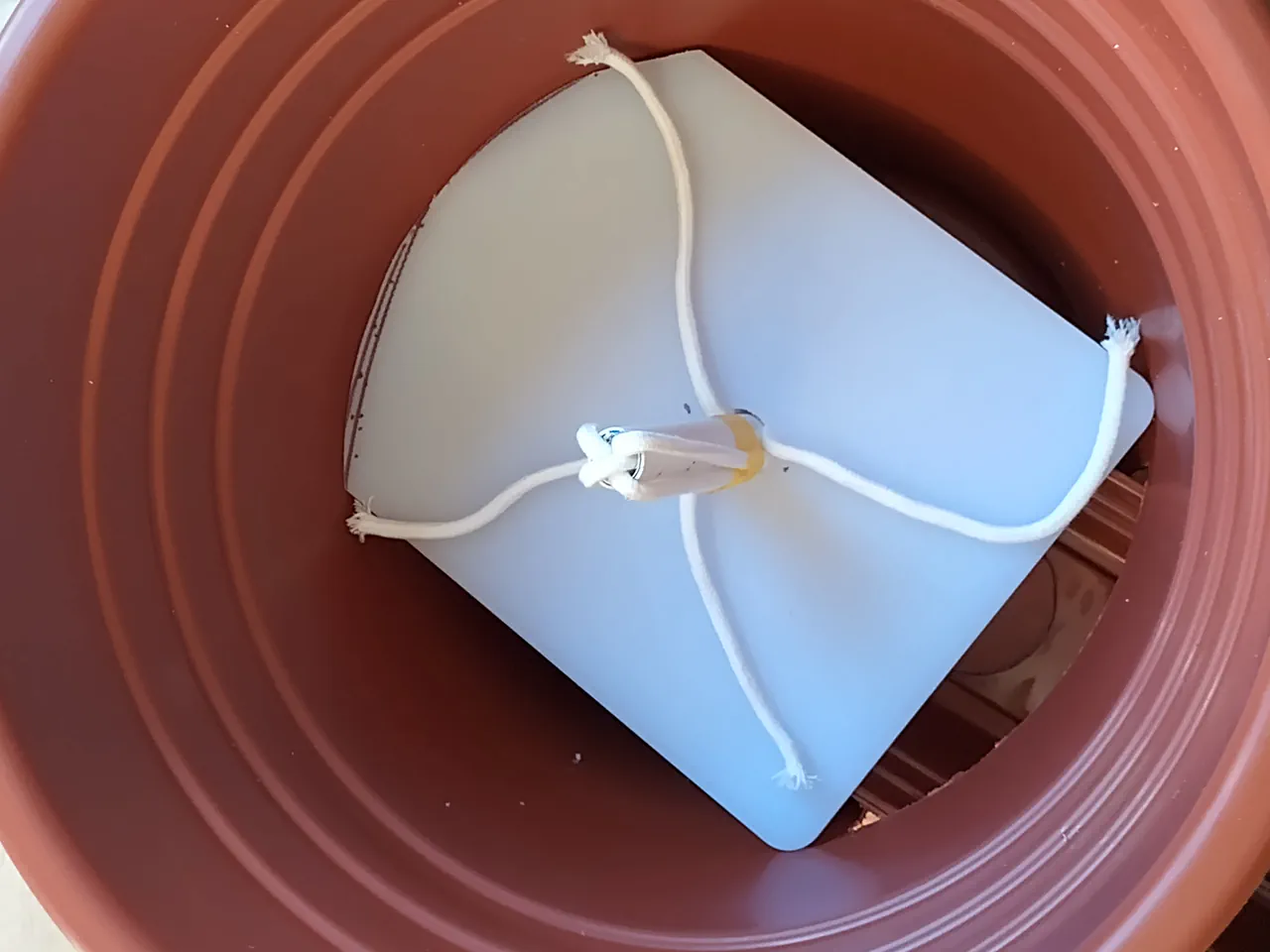 Wicking rope passing up through the hole in the chopping board platform, spreading out above
